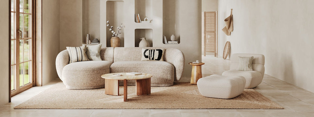 Salon bohème chic avec canapé arrondi en bouclé beige, table basse bois, tapis jute et lumière naturelle – Maison Pavane