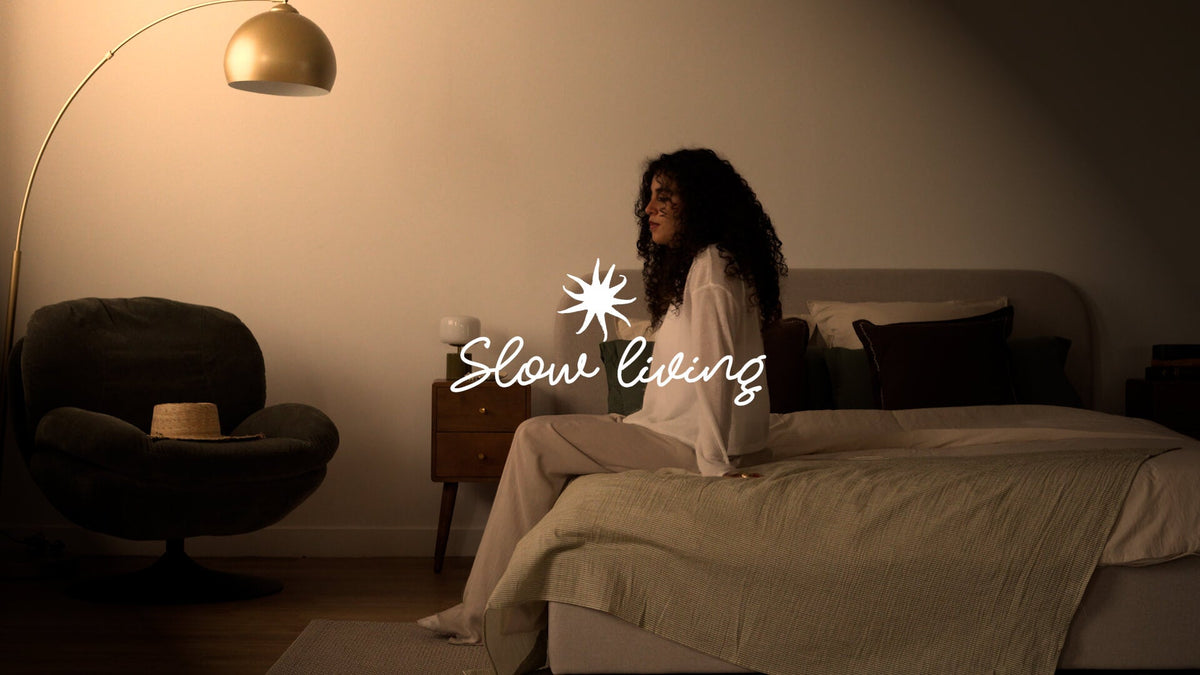 Chambre slow living, linge de lit coton rayé vert, table de chevet vintage en bois, lumière tamisée dorée – Maison Pavane
