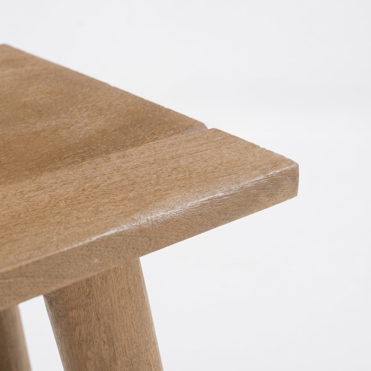 Détail de l'angle de l'assise en bois de manguier marron du tabouret Toxis - Maison Pavane
